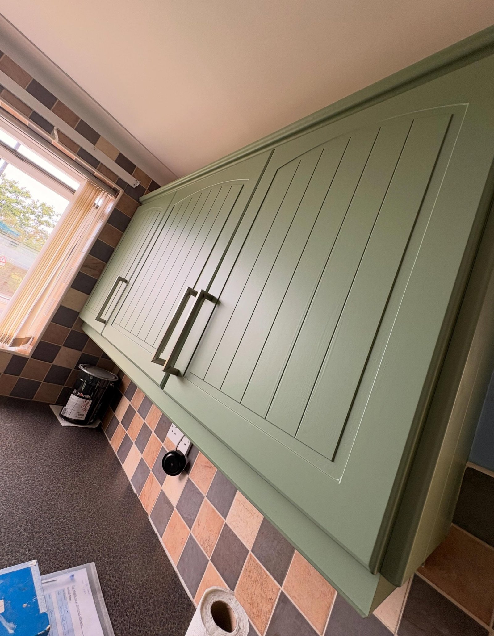 Sage green kitchen corner with a freestanding white dishwasher, patchwork tile backsplash, and a Belling kettle on the counter.
