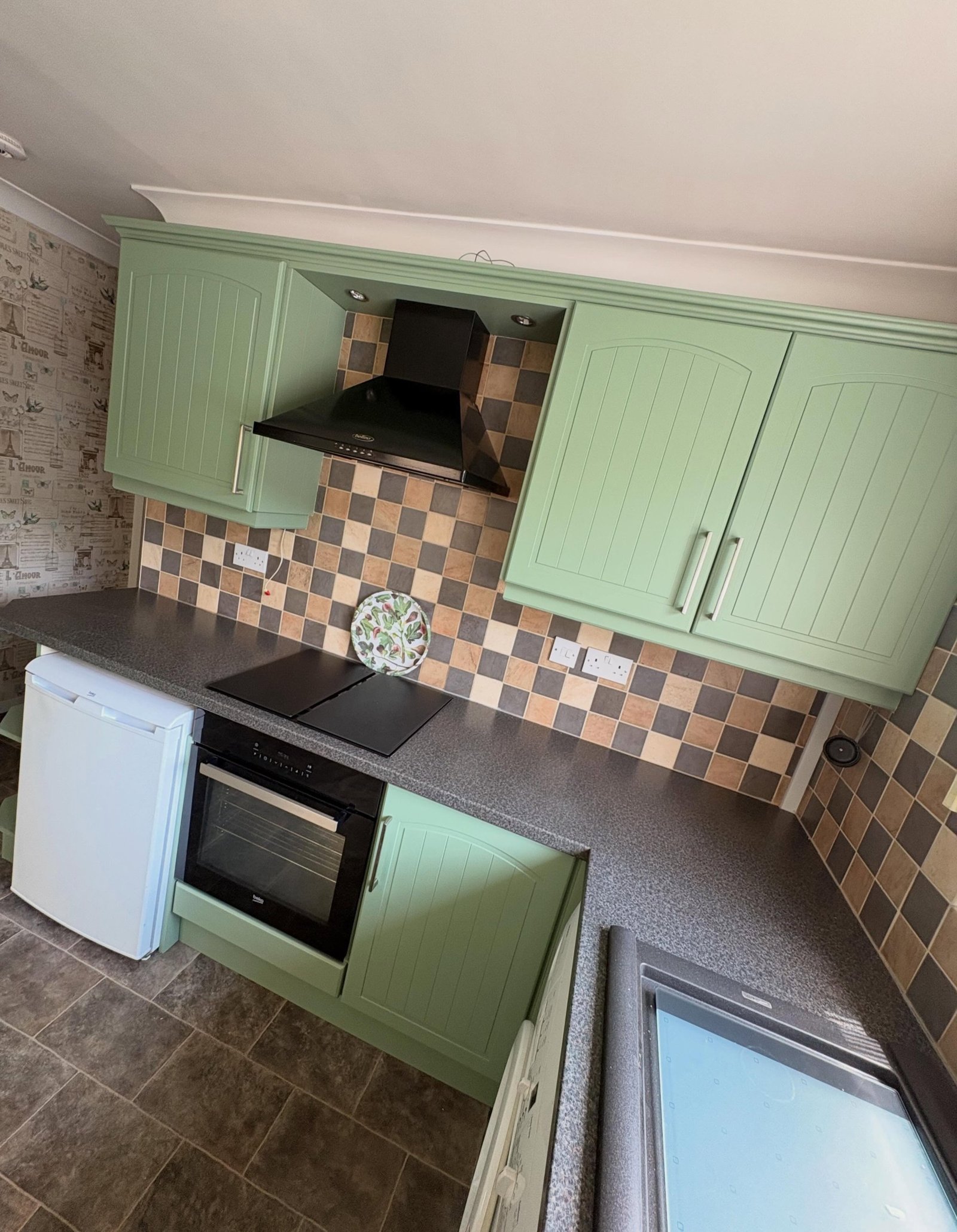 Wide view of the completed U-shaped kitchen painted in Farrow & Ball Breakfast Room Green with the window over the sink and the original floor tile.