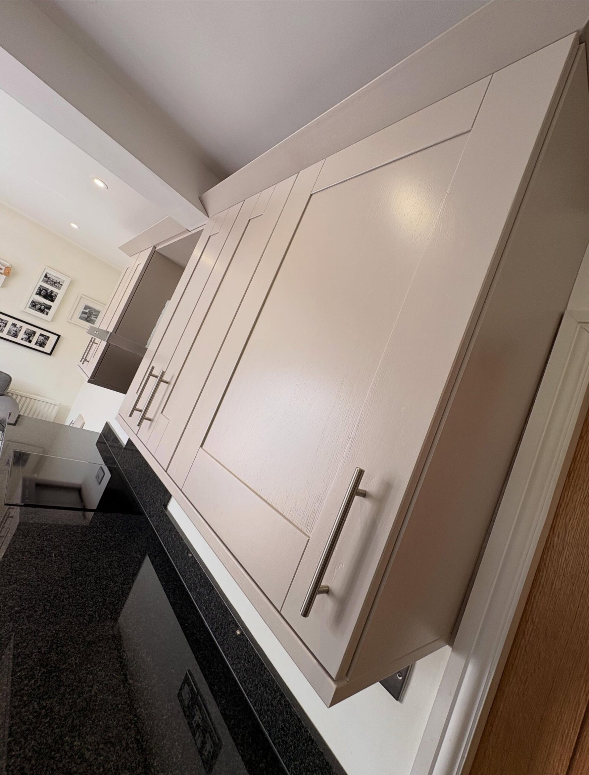 Low angled shot of a cashmere satin wall cabinet, showing the ceiling line, side panel, and bar handle from below.