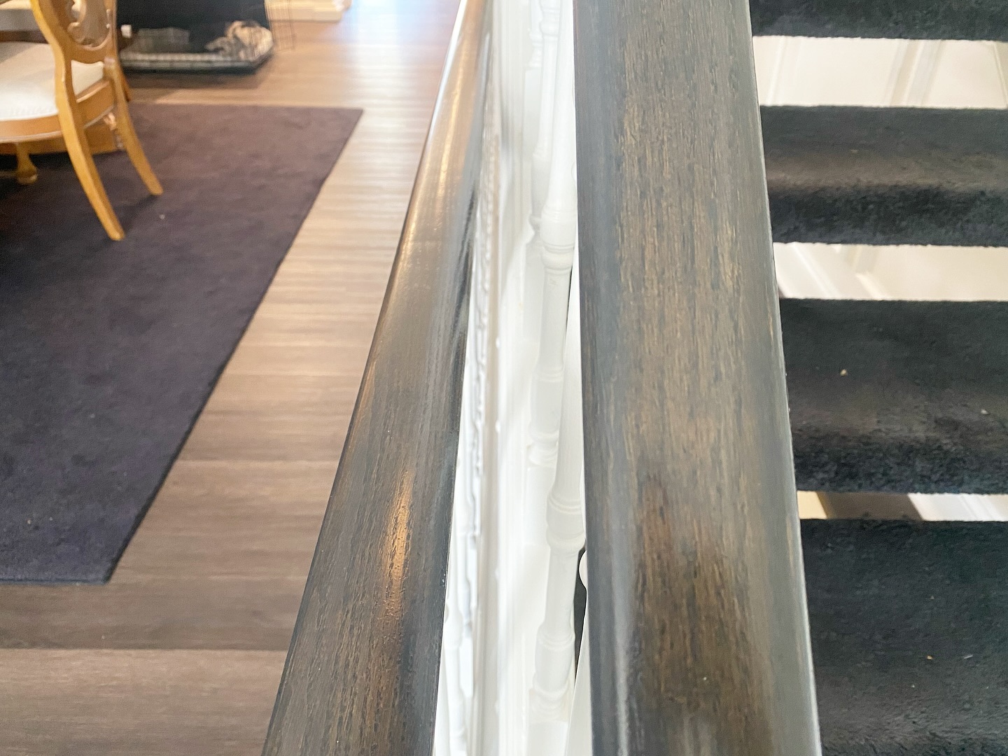 Close up of the finished handrail showing the custom Minwax stain blend with visible wood grain and a smoky dark tone.