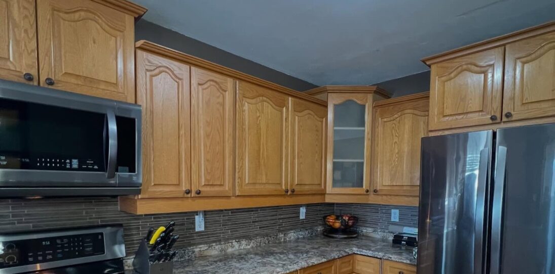 She painted honey oak cabinets Benjamin Moore Revere Pewter: same arched doors, a new kitchen