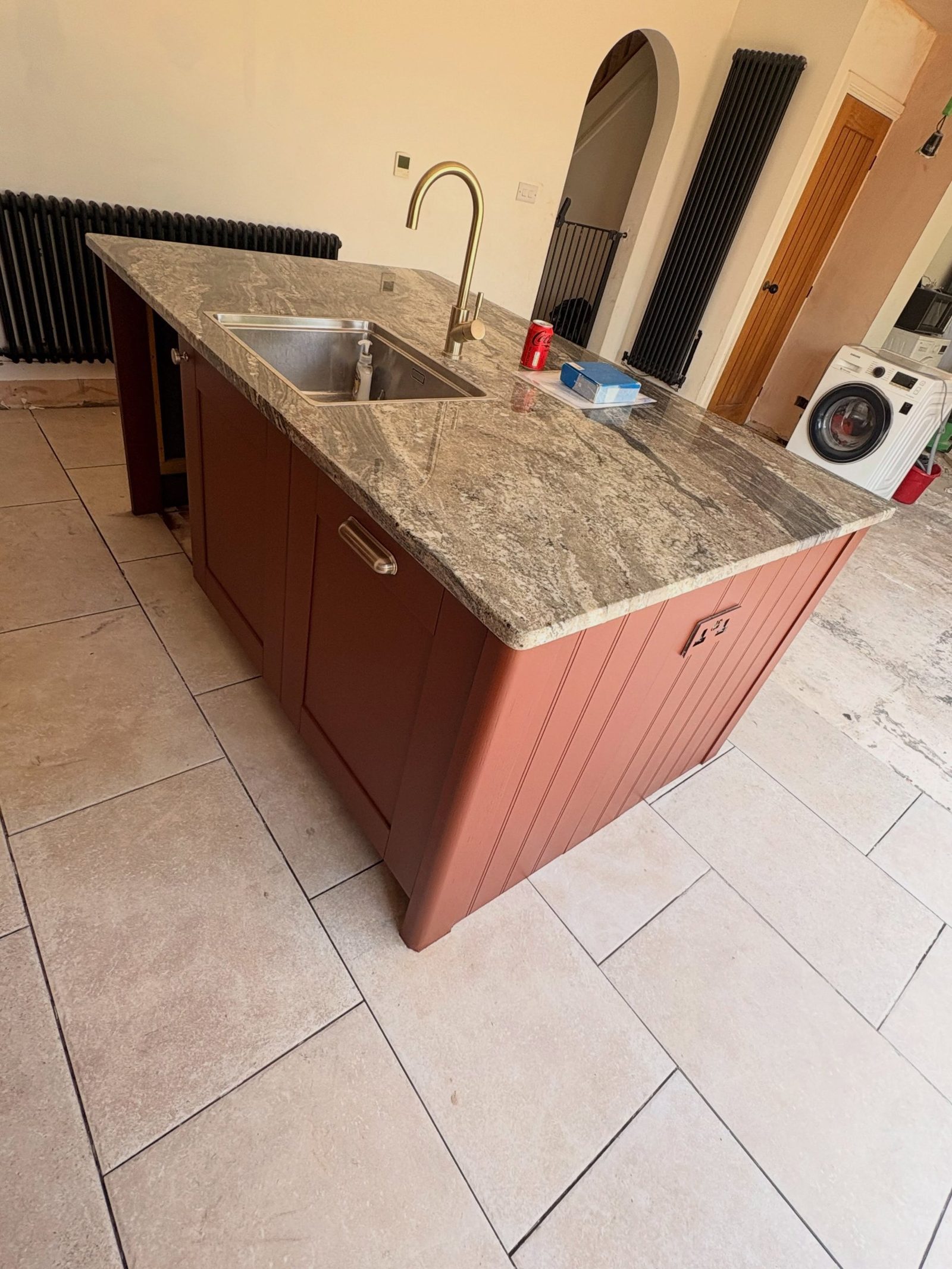 Kitchen island in the middle of being resprayed, with primer and masking still in place around the cabinets.