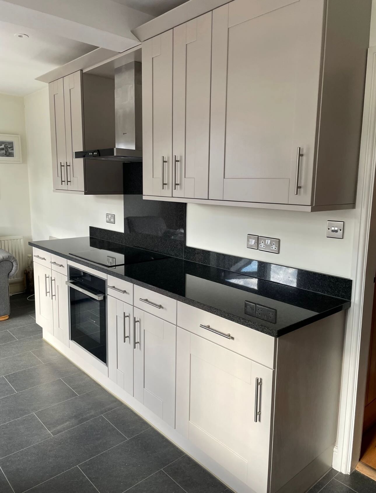 Honey oak base cabinet in a kitchen corner with a small TV on the counter, blinds behind, and a pet bowl on the tiled floor.
