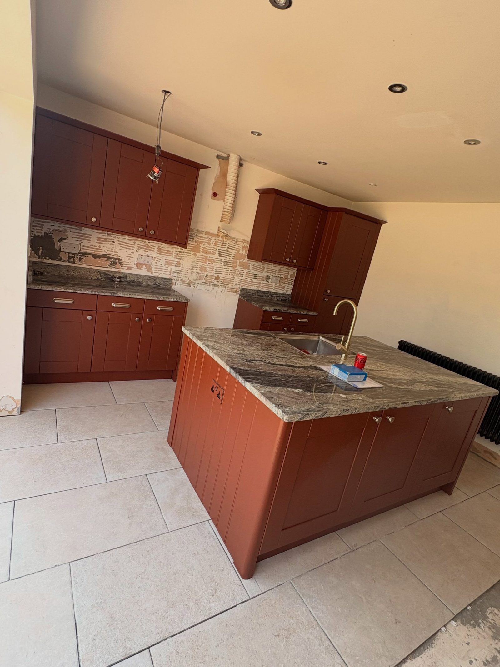 Chrome cup-pull on an Etruscan Red cabinet door below the granite worktop on the kitchen island.